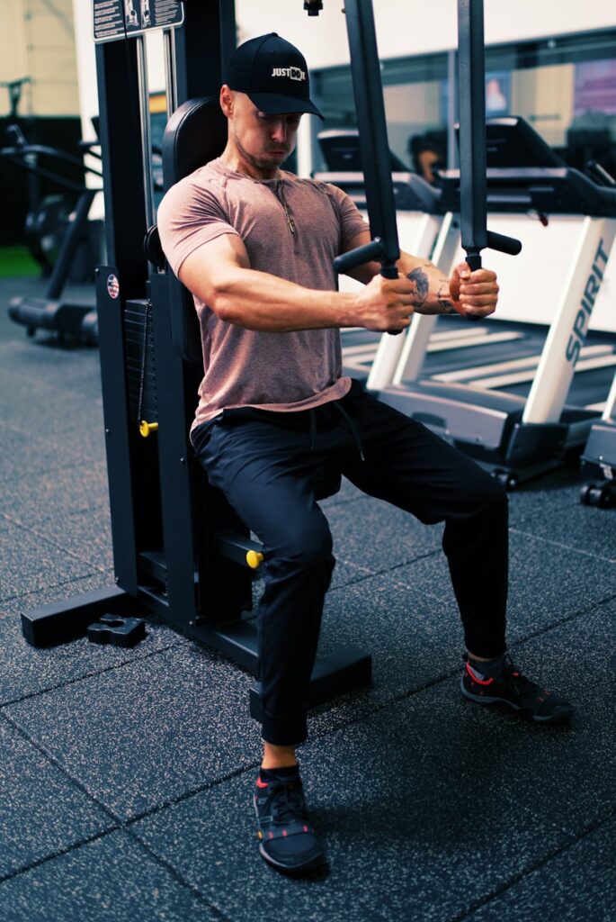 Photo by Gordon Cowie man in gray t-shirt and black pants sitting on black and white metal bar